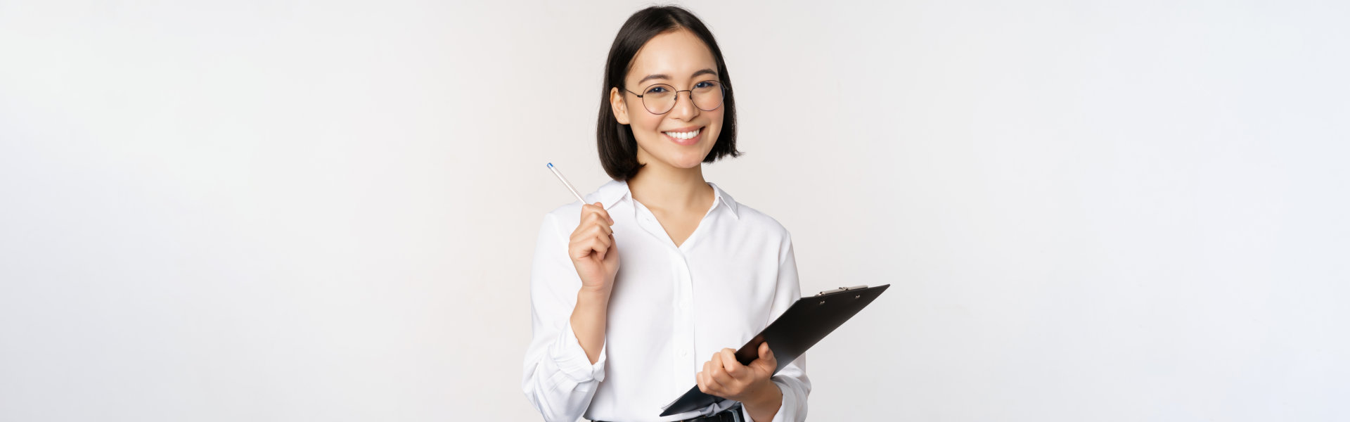woman holding a clipboard and a pen smiling